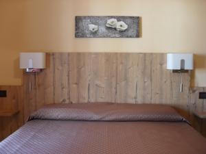 a bedroom with a bed with two lights on the wall at Ristorante Albergo Da Maurizio in Cravanzana