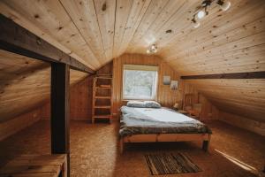 a bedroom with a bed in a wooden cabin at Nītaigā Holiday Home in Saunags