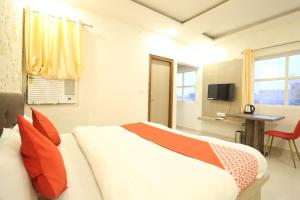 een slaapkamer met een bed met oranje kussens en een bureau bij HOTEL UMA PALACE in Gorakhpur