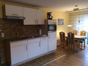 a kitchen with white cabinets and a table with chairs at Haus Achterum in Langeoog