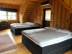 Duas camas num quarto com paredes e janelas de madeira em Emajõe puhkemaja em Sarakuste