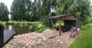 um gazebo com um banco ao lado de um lago em Emajõe puhkemaja em Sarakuste