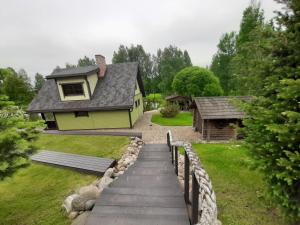 una casa amarilla con una pasarela que conduce a un patio en Emajõe puhkemaja, en Sarakuste