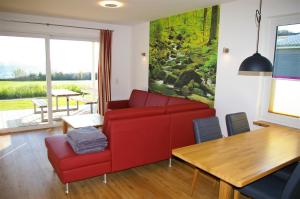 a living room with a red couch and a table at Witt am See L in Klein Wittensee