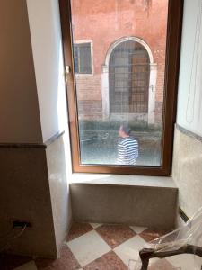 Um homem está a olhar pela janela. em Luxury Apartment in San Marco with Canal View em Veneza