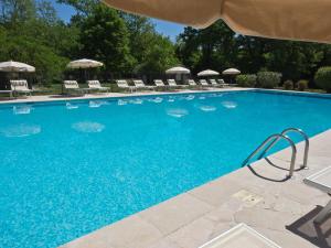 uma grande piscina azul com cadeiras e guarda-sóis em Hotel-Restaurant Le Moulin De La Camandoule em Fayence