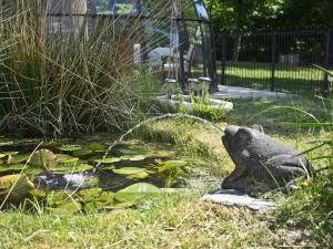 uma estátua de um urso sentado ao lado de um lago em Hotel-Restaurant Le Moulin De La Camandoule em Fayence