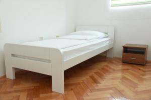 Cama blanca en habitación con suelo de madera en NP Sutjeska Paviljon A, en Tjentište