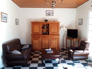 ein Wohnzimmer mit 2 Ledersofas und einem TV in der Unterkunft Maison dans Quartier Calme in Lacanau-Océan