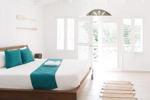 um quarto branco com uma cama com almofadas azuis em El Mosquito Boutique Hotel Playa Bonita em Las Terrenas