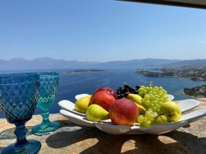 a plate of fruit on a table with two wine glasses at Villa Muse in Agios Nikolaos