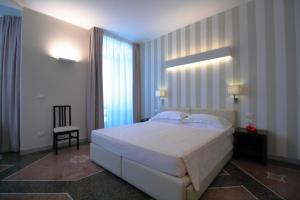 sypialnia z dużym białym łóżkiem i oknem w obiekcie Hotel Vittoria w Genui