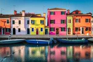 a group of boats in the water in front of buildings at BRUNA HOLIDAYS HOUSE in Burano