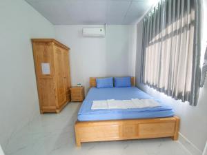 a bedroom with a bed with blue sheets and a window at MƯỜI HOMESTAY in Con Dao