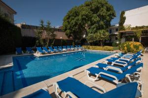 a pool with blue and white chaise lounge chairs at Hotel Yola in Altafulla