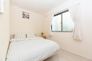 a white bedroom with a bed and a window at 足跡 ASHIATO in Tokyo