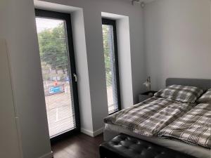 1 dormitorio con 1 cama y 2 ventanas grandes en Business Apartament, en Leszno