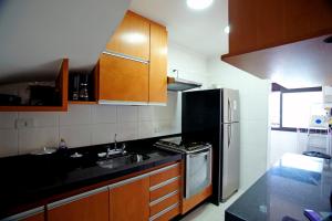 a kitchen with wooden cabinets and a black counter top at Conforto em Campos in Campos do Jordão
