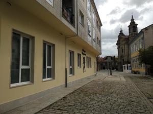 an empty street with a yellow building and a church at Albergue & Rooms Murgadán in Padrón