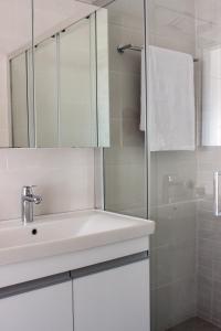 a white bathroom with a sink and a shower at New and Airy Apartment few steps from the beach in Sougia