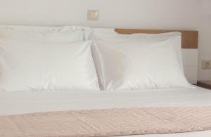 a bed with white sheets and pillows at New and Airy Apartment few steps from the beach in Sougia
