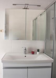 a white bathroom with a sink and a mirror at New and Airy Apartment few steps from the beach in Sougia