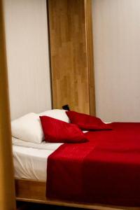 a bed with red sheets and white pillows at Sunset Hotel in Jūrmala