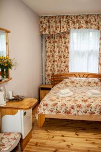 1 dormitorio con cama, mesa y ventana en Sunset Hotel, en Jūrmala