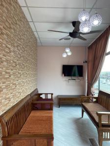a living room with benches and a tv and a wall at Ilham Bonda 2 Homestay in Cukai