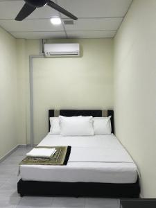 a bed with white sheets and pillows in a room at Ilham Bonda 2 Homestay in Cukai