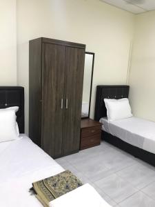 een slaapkamer met 2 bedden en een houten kast bij Ilham Bonda 2 Homestay in Cukai