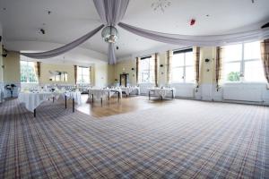 Habitación grande con mesas y sillas. en Beveridge Park Hotel, en Kirkcaldy