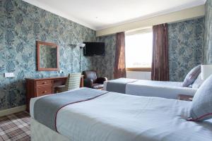 Habitación de hotel con 2 camas y TV en Beveridge Park Hotel, en Kirkcaldy