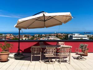 a table and chairs under an umbrella on a roof at Apartments Apolon Izola in Izola