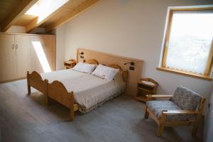 a bedroom with a bed and a chair and a window at Agritur Rizzi di Inama Ugo in Coredo