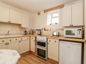 a kitchen with white cabinets and white appliances at Yeoman Cottage in Crewkerne