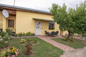ein gelbes Haus mit einem Tisch und Stühlen im Hof in der Unterkunft Apartman Peric in Ðakovo