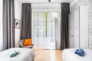 sypialnia z 2 łóżkami, krzesłem i oknem w obiekcie Pod arkadami w Warszawie