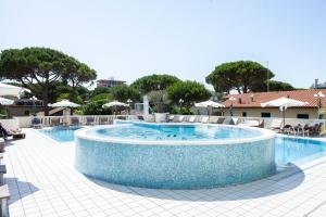 uma grande piscina com cadeiras e guarda-sóis num resort em Hotel Conchiglia em Cervia