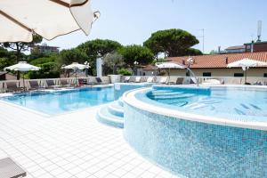 uma grande piscina com cadeiras e guarda-sóis em Hotel Conchiglia em Cervia