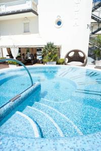 a swimming pool in a hotel with a blue tile floor at Hotel Conchiglia in Cervia