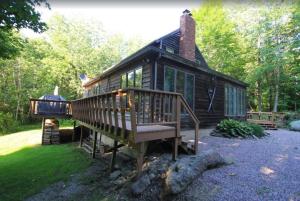 a small cabin with a large deck and a grill at Quaint Stowe Cabin in Stowe