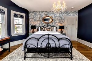 Un dormitorio con una cama con paredes azules y una lámpara de araña. en Slaymaker & Nichols Gastro House & Inn, en Charlottetown