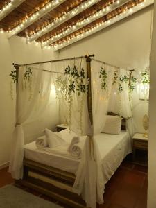 a bedroom with a canopy bed with white curtains at HOTEL BOUTIQUE EL FARO BY AROMAX in Medellín
