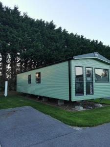 a green tiny house sitting in the grass at Rustling Pines at Knaresborough Lido in Harrogate