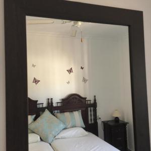 a mirror in a bedroom with butterflies on the wall at Casa Mariposa in Alhaurín el Grande