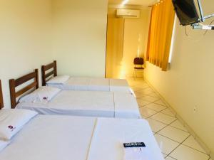 a room with three beds and a television in it at Hotel Oliveira - By UP Hotel in Ipatinga
