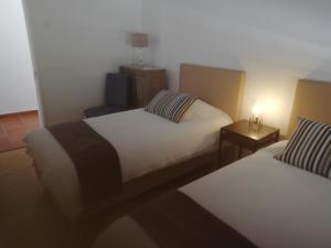 a hotel room with two beds and a night stand at Casa do Jardim in Beja