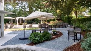 a patio with tables and chairs and an umbrella at Auberge du Vieux Cedre in Enghien