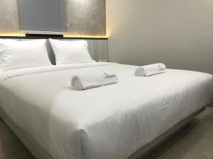a large white bed with two towels on it at LeGreen Suite Semanggi in Jakarta